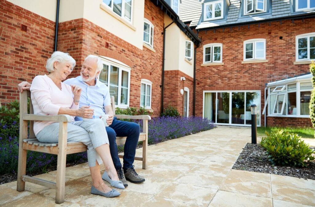An older couple sit together on a bench outside a senior living community after going on a tour to discuss their thoughts